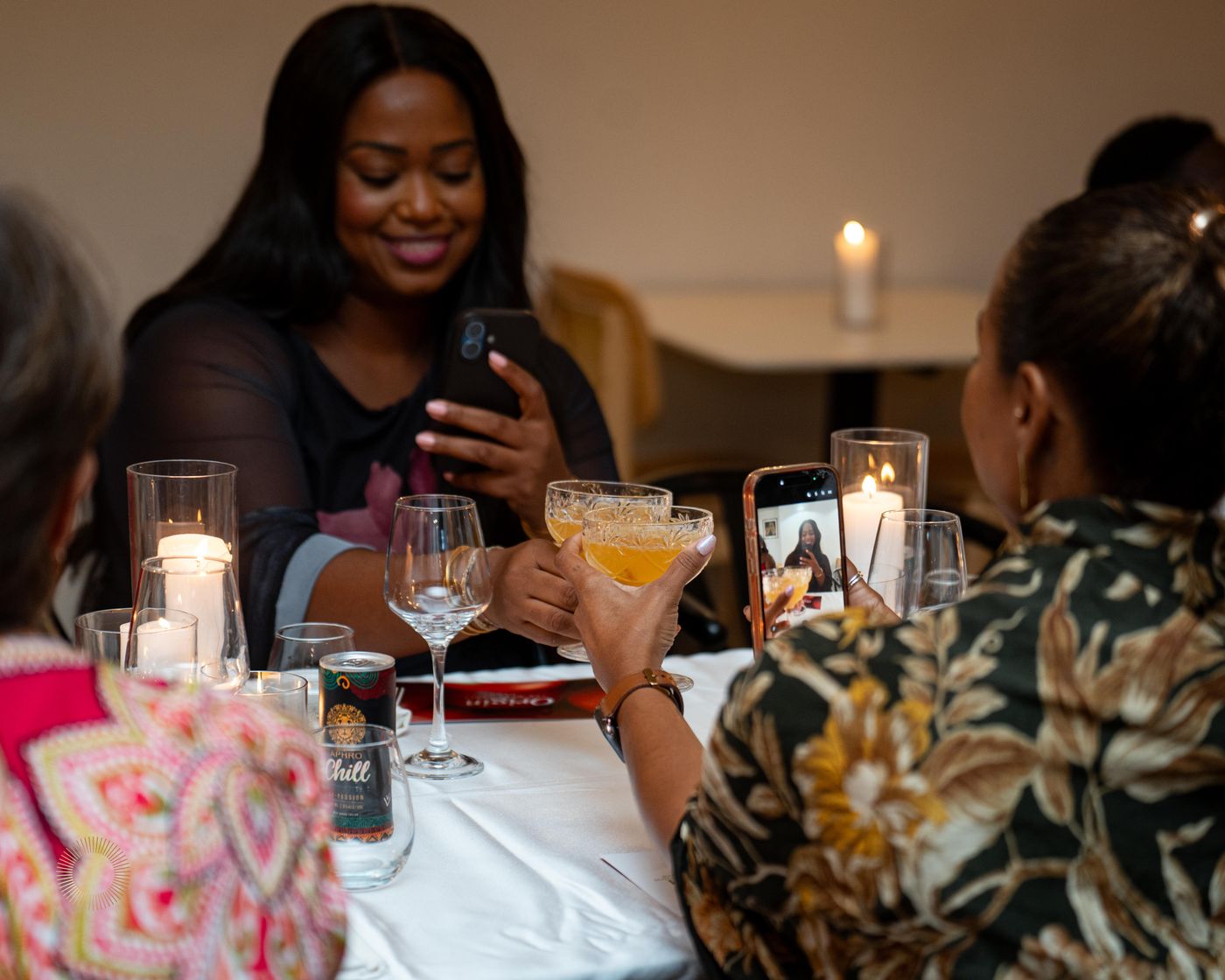 Friends toasting Aphro cocktails at a candlelit table