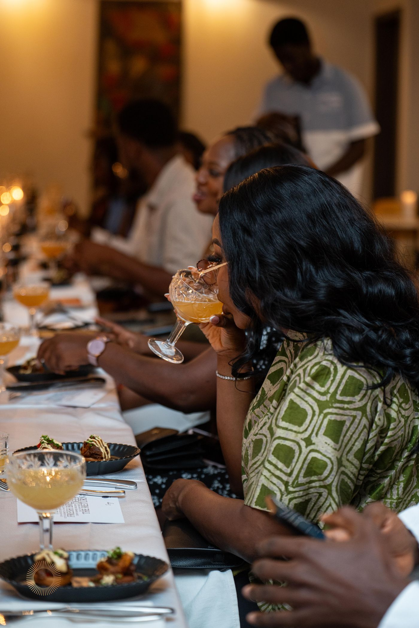 A long communal dinner table with guests sipping Aphro cocktails