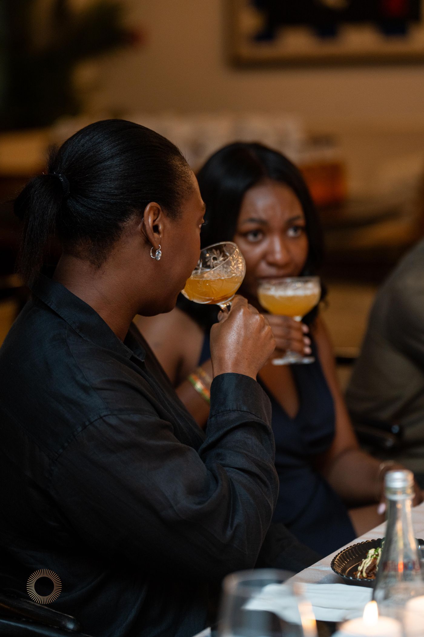 Two women sipping Aphro cocktails together at dinner
