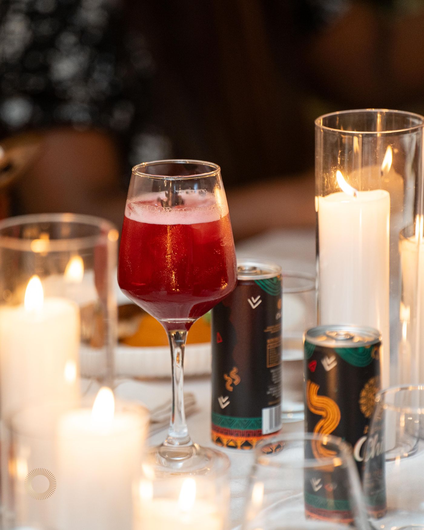 A red Aphro cocktail beside Aphro Chill cans and candlelight