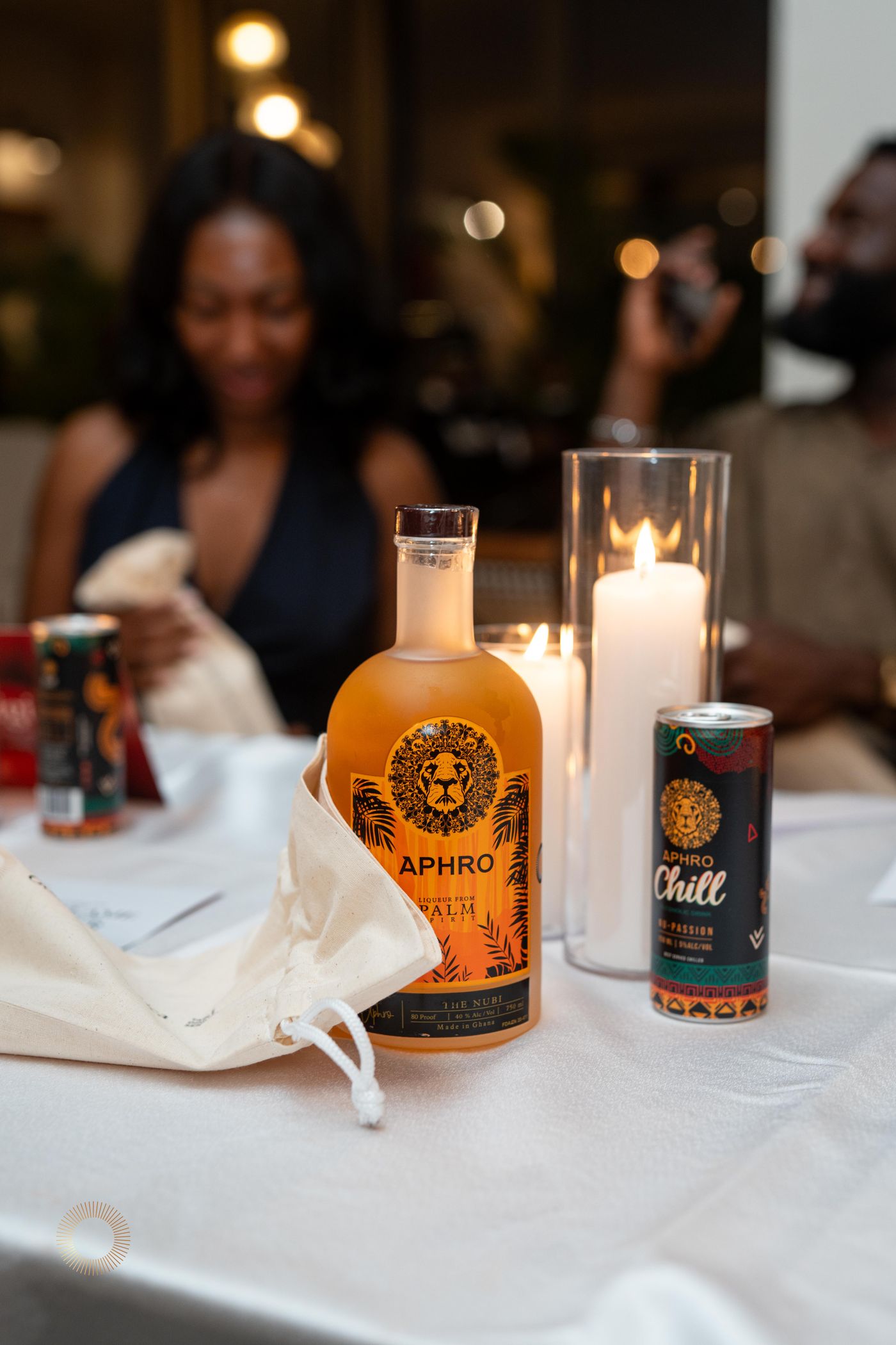 A bottle of The Nubi and an Aphro Chill can on a candlelit table